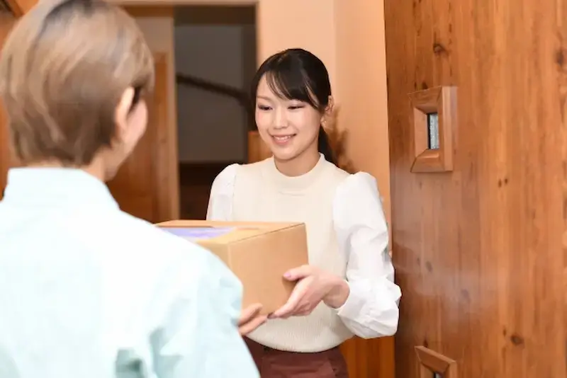 宅配クリーニングの荷物を受け取る女性